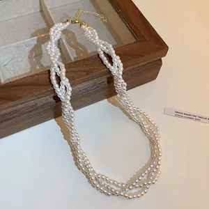 Elegant multi-strand twisted pearl necklace with vintage gold clasp on wooden frame