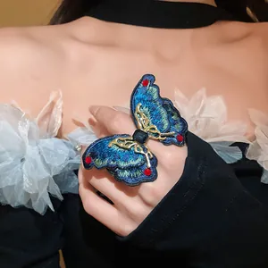 Detailed view of large blue embroidered butterfly ring featuring gemstone and gold accents