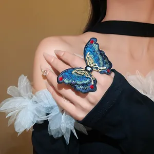 Close-up detail of an ethnic style blue embroidered butterfly ring with red crystals
