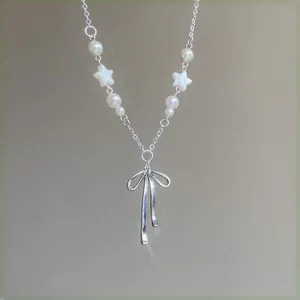 Detailed view of silver bow pendant necklace with pearls and star-shaped accents