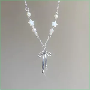 Detailed close-up of a French style bow pendant pearl necklace with white star beads