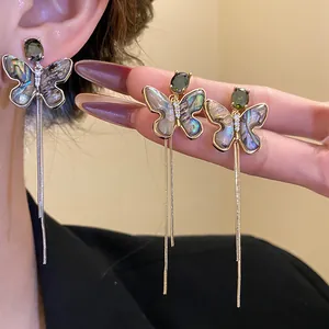 Detail view of butterfly tassel earrings with zircon and colorful sea shell wings.