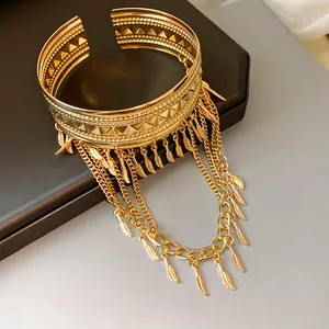 Vista dettagliata di un bracciale da braccio boho dorato con ciondoli a piuma e catene a nappa