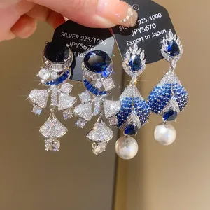 Close-up detail of luxury silver zircon drop earrings with blue stones and pearls