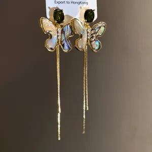 Detailed macro view of vintage butterfly drop earrings with shell wings and gold tassels.