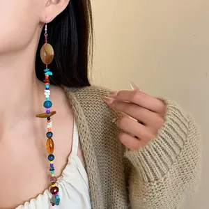 Orecchini lunghi boho in pietre naturali colorate indossati da una modella.