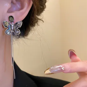 Detail view of 18K gold plated butterfly tassel earring with iridescent shell wings