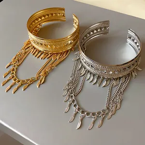 Dettaglio di bracciali a piume in oro e argento con catene e finiture curate