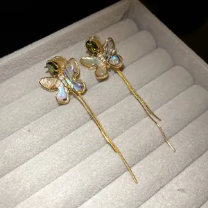 Close-up of 18K gold plated butterfly clip-on earrings with shell and long tassels