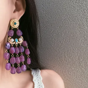 Detailed view of vintage elegant purple tassel earrings worn by a model in a close-up