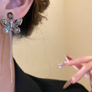 Close-up of 18K gold plated zircon butterfly earring with shell wings and long tassels