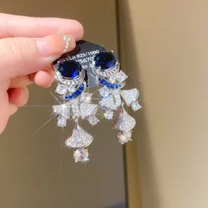 Detail view of silver drop earrings with blue sapphire-like stones and sparkling zircons