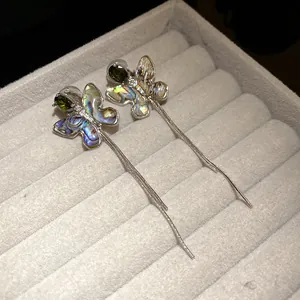 Detailed view of 18K gold plated butterfly tassel earrings with zircon and shell.