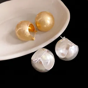 Minimalist geometric gold and silver ball hoop earrings set on a dish