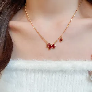 Gros plan d'un collier doré élégant orné d'un pendentif en émail de cheval rouge.
