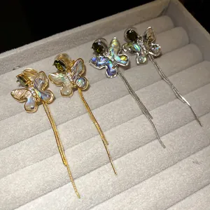 Detail view of butterfly tassel clip earrings with abalone shell and green zircon