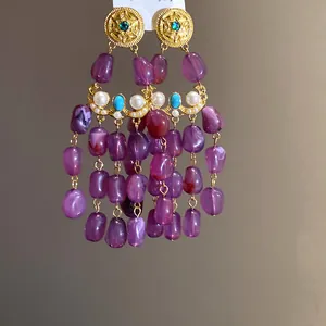 Close-up of elegant vintage tassel earrings featuring purple stones and pearl details