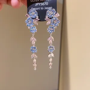 Detailed macro view of elegant blue zircon flower and pink crystal tassel earrings