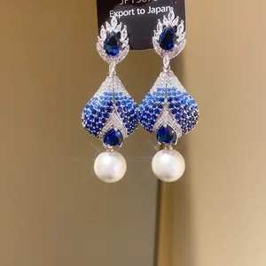 Detailed view of teardrop earrings with blue gradient zircons and white pearls