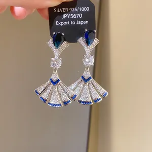 Detail of silver drop earrings with blue and clear zircon stones in a fan shape