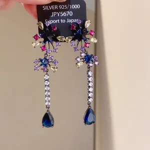 Close-up detail of multi-colored zircon star earrings with blue teardrop-shaped tassels