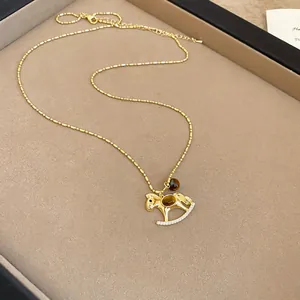 Détail d'un pendentif cheval à bascule doré orné d'une pierre œil de tigre et de cristaux.