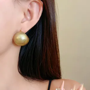 Detailed close-up showing a large minimalist gold semi-sphere stud earring on ear