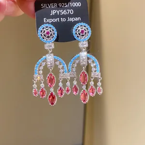 Ornate chandelier earrings with turquoise beads and pink stones on a display card