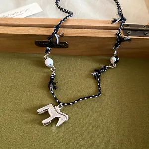 Gros plan d'un collier en cordon tressé noir et blanc avec pendentif cheval argenté