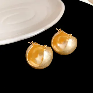 Close-up of golden geometric ear buckles with elegant matte and polished textures