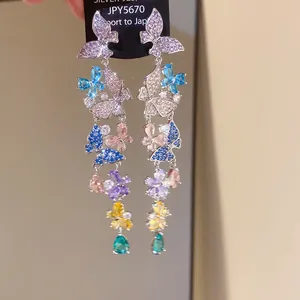 Macro detail of multicolored butterfly tassel earrings with sparkling zircons and teal drop