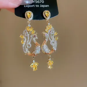 Detailed close-up of luxurious gold peacock earrings with sparkling yellow zircons