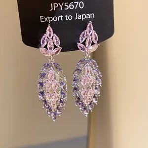 Macro detail of elegant marquise-cut pink and purple zircon drop earrings on silver needles.