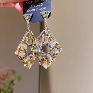 Detailed view of luxury rhombus-shaped earrings with colorful sparkling zircon crystals.