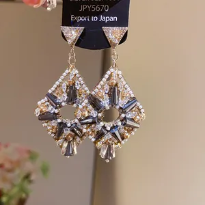 Detail view of luxurious geometric zircon earrings with grey stones and silver pin