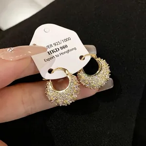 Elegant gold-plated hoop earrings with shimmering cubic zirconia stones on a display card.