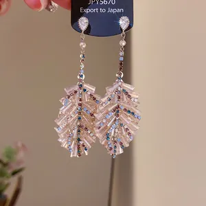 Close-up macro view of elegant crystal leaf tassel earrings featuring colorful sparkling stones