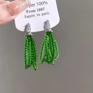 Detail of silver needle zircon earrings with elegant green beaded tassels