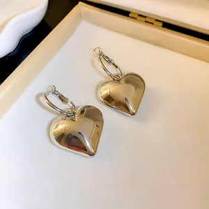 Vista dettagliata di orecchini a cuore in argento minimalisti in una scatola per gioielli beige