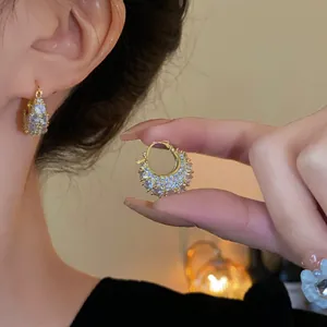 Detailed close-up of gold-plated hoop earrings with sparkling cubic zirconia stones