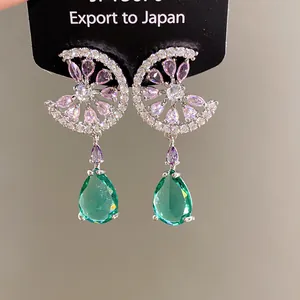 Detailed view of silver stud earrings with pink zircons and green water drop gems
