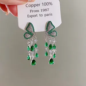 Macro detail of elegant zircon butterfly earrings with green teardrop tassel drops