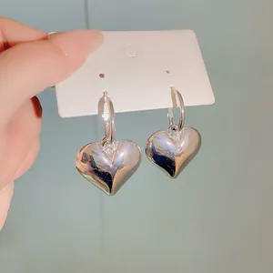Primo piano di eleganti orecchini a cerchio a forma di cuore argento con finitura lucida.