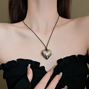 Dettaglio di una grande collana con ciondolo a cuore in argento lucido su cordoncino