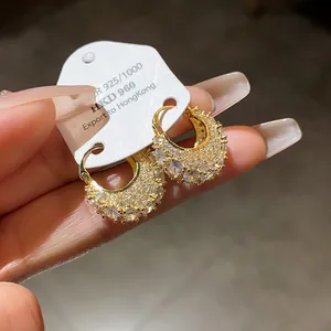 Detailed macro view of gold plated hoop earrings with shimmering cubic zirconia stones