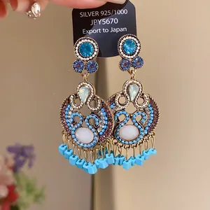 Detail view of ornate S925 silver needle earrings with blue stones and tassels