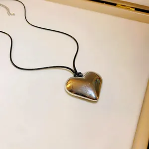 Primo piano dettagliato di un grande ciondolo a cuore in metallo argentato.