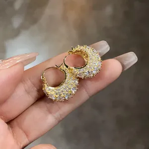 Detailed close-up of gold-plated hoop earrings encrusted with sparkling cubic zirconia stones