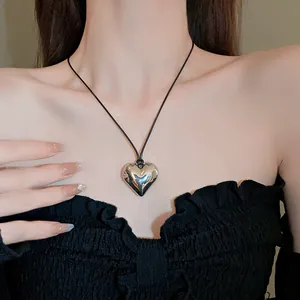 Primo piano di una collana con ciondolo a cuore in argento lucido su cordoncino