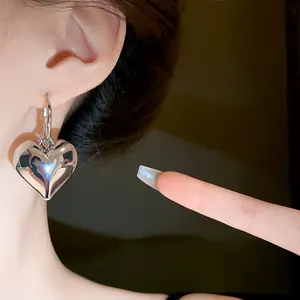Dettaglio di un orecchino a cerchio a cuore argentato con superficie lucidata a specchio